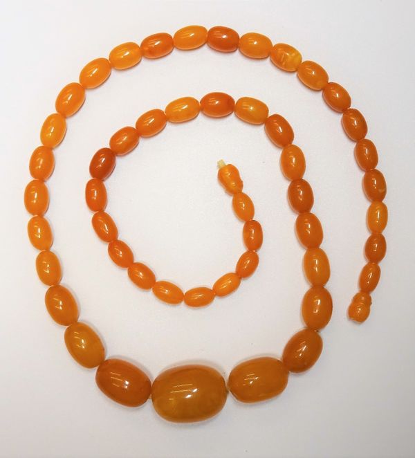 A single row necklace, of graduated varicoloured butterscotch coloured oval amber beads, on a threaded clasp, length of necklace including clasp 78cm,