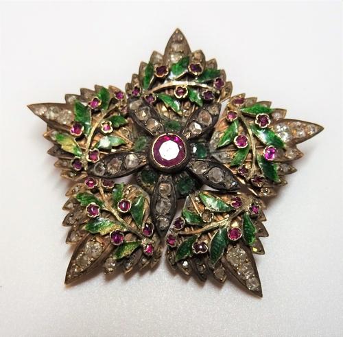 A gold, diamond, ruby set and green enamelled brooch, designed as a five pointed star and a green enamelled wreath, mounted with the principal cushion