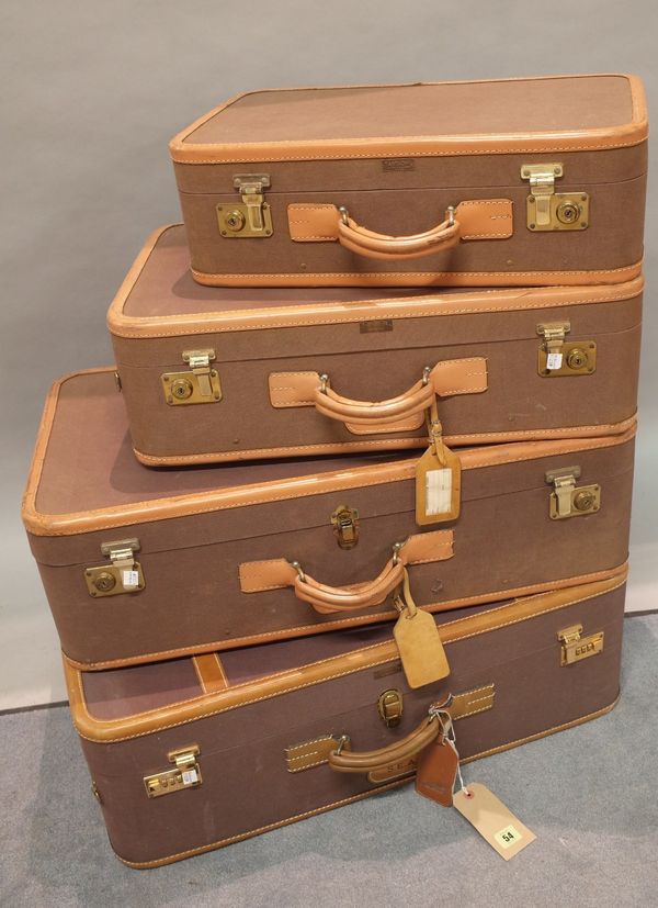 A group of four early 20th century leather bound canvas suitcases, the largest 73cm wide x 24cm high, (4).