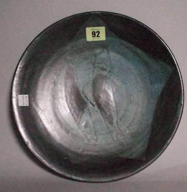 A studio pottery stoneware plate possibly by Bernard Leach, relief decorated with two fish, indistinct seal marks, 27cm diameter. Provenance: Woolley