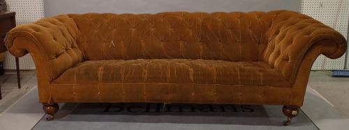 A late Victorian mahogany framed Chesterfield sofa, with roll over arms and brown button back upholstery on ball supports, 220cm wide x 75cm high.