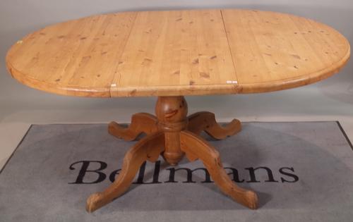 A 20th century pine circular extending dining table on baluster column and four downswept supports, one extra leaf, 122cm deep x 173cm fully extended
