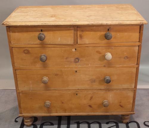 An early 20th century pine chest of two short and three long graduated drawers on turned supports, 102cm wide x 98cm high.