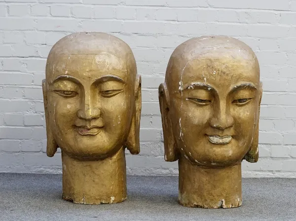 A pair of large gold painted Buddhistic style heads with elongated ears, each 82cm high.