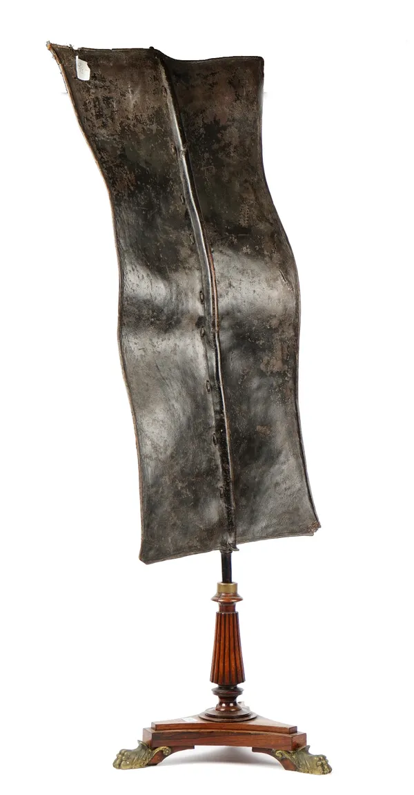 An African Tribal leather battle shield, 104cm high and 43cm wide, mounted on a Regency rosewood tri-form base.