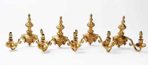 A set of four 20th century gilt metal twin branch wall lights, with flame finials, fitted for electricity, 28cm high, (4).