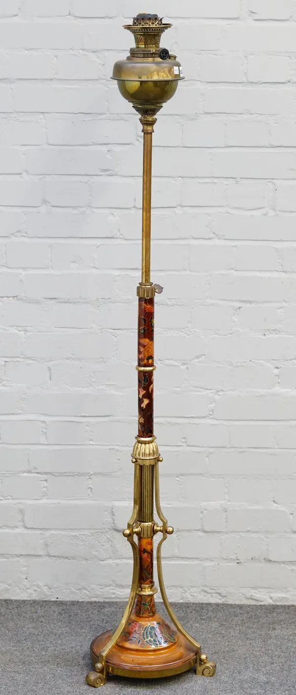 A late Victorian pottery and brass adjustable standard lamp, the circular reservoir above a sectional pottery mounted stem and circular base decorated