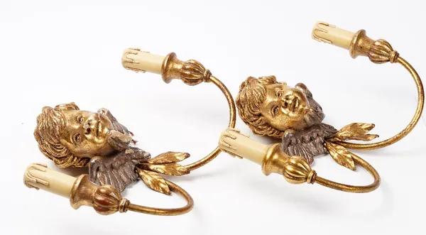 A pair of early 20th century gesso gilt metal and carved wood wall lights, modelled as Cherubs faces, 35cm wide.