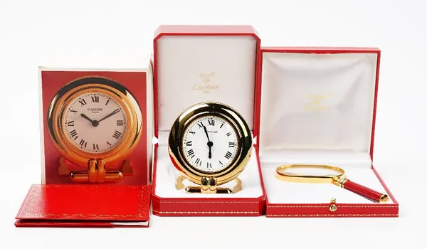 A Cartier 'colisee' quartz travel alarm clock, circa 1998, white dial with Roman numerals, to a gilt metal case with folding stand, with original Cart