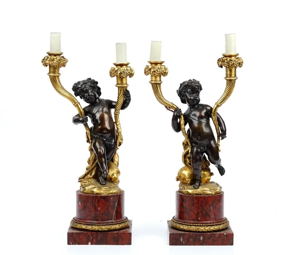 A pair of Napoleon III ormolu, patinated bronze and rouge griotte marble twin light candelabra, in the Louis XVI style, each modelled as cherub suppor