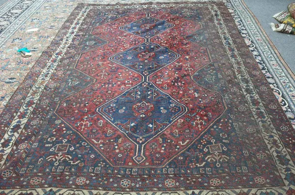 A Shiraz carpet, Persian the madder field with three indigo diamonds, matching spandrels and surround, all with flower motifs, birds and animals, an i