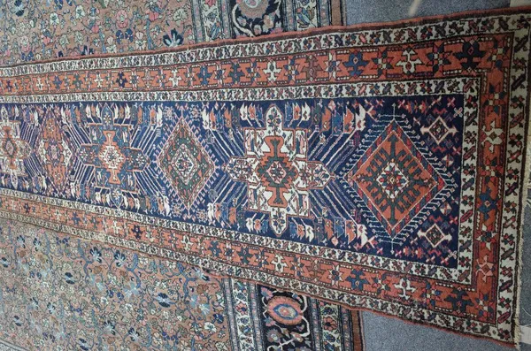 A North Western Persian runner, the indigo field with eleven single medallions, a madder star and bracket border, 533cm x 98cm.