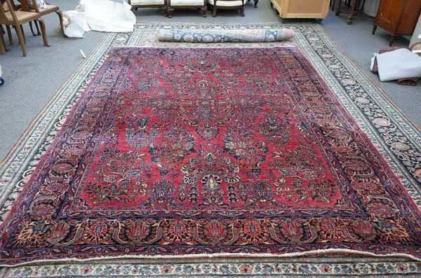 A Sarough carpet, the madder field with a central carnation design and other large floral sprays; a dark indigo border with palmette and leaf design,