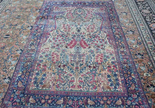 A Kerman prayer rug, Persian, the beige mehrab with abundantly floral trees rising to an indigo floral arch; a dark indigo bird and floral tree border