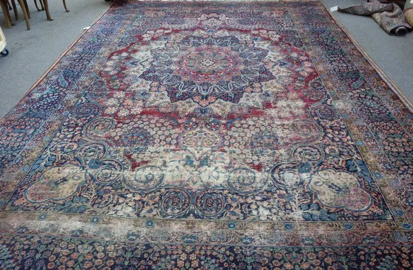 A Kerman carpet, Persian, the madder field with a bold rosette medallion, indigo spandrels, all with floral sprays; an indigo floral spray border, 510