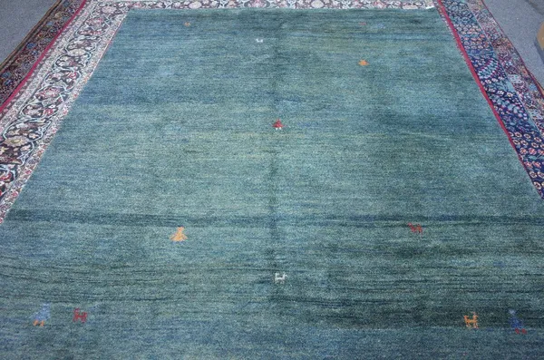 A Gabeh carpet, Persian, the plain petrol green field with single mirror animals and figures, 290cm x 245cm.