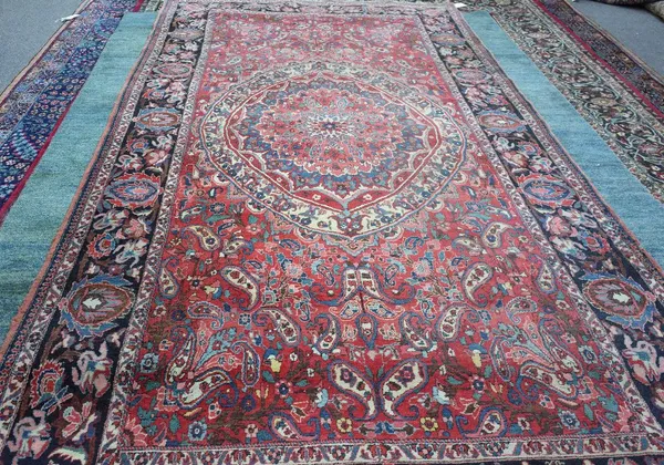 A Mahal carpet, Persian, the madder field with a bold rosette medallion, tulip spandrels and other floral designs; the dark indigo border with palmett