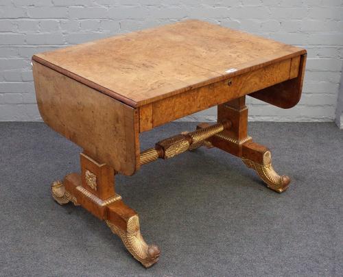 A Regency parcel gilt burr elm and elm banded sofa table, with single frieze drawer on trestle supports and leaf scroll feet, united by spiral turned