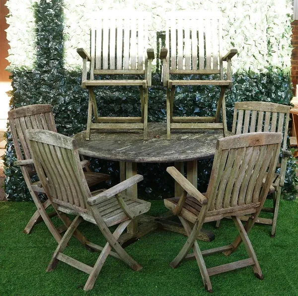 A teak circular garden table of slatted construction, 130cm diameter, together with six folding chairs, (7).