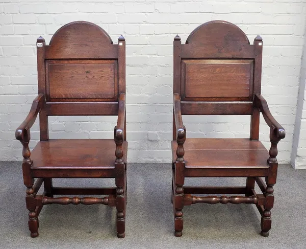 A pair of 17th century style oak panel back open armchairs on turned supports, 59cm wide x 120cm high (2).