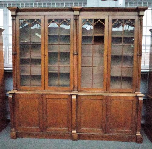 A Victorian oak Gothic revival bookcase cabinet with four arched astragal glazed doors divided by cluster columns over four panelled cupboards on a pl