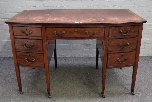 An Edwardian tulip wood banded mahogany bowfront writing desk with seven drawers about the knee on tapering square supports, 122cm wide x 76cm high.