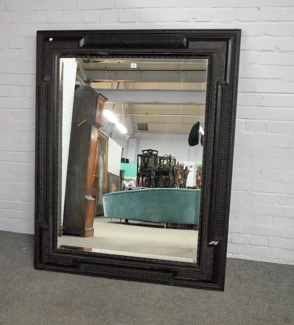 An 17th century style ebonised wall mirror with wriggle work cushion frame about the bevelled mirror plate, 122cm wide x 152cm high.