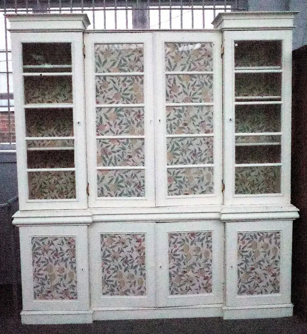 A cream painted display cabinet/cupboard, the four glazed doors over four panelled cupboards inset with William Morris pattern wallpaper panels, 222cm