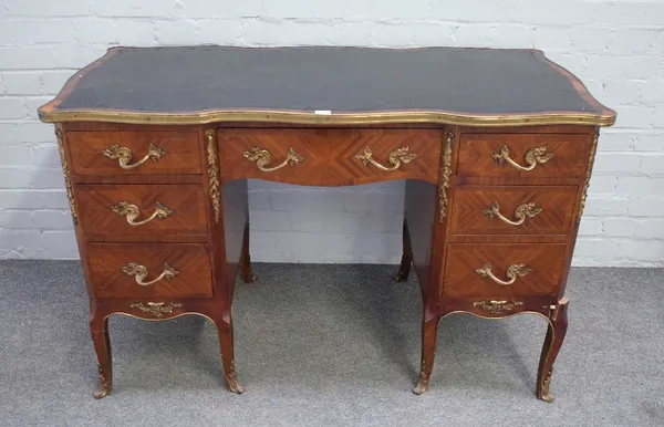 A Louis XV style gilt metal mounted rosewood and mahogany writing desk, of serpentine outline, with seven drawers about the knee, on scroll supports,