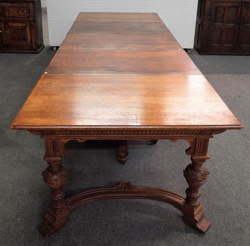 A 19th century German oak extending dining table on carved baluster supports united by shaped stretcher, 112cm wide x 138cm long, 440cm long fully ext