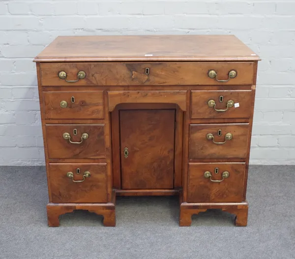 A mid-18th century figured yew kneehole writing desk, with fitted drawer over six drawers about the kneehole cupboard, on bracket feet, 95cm wide x 82