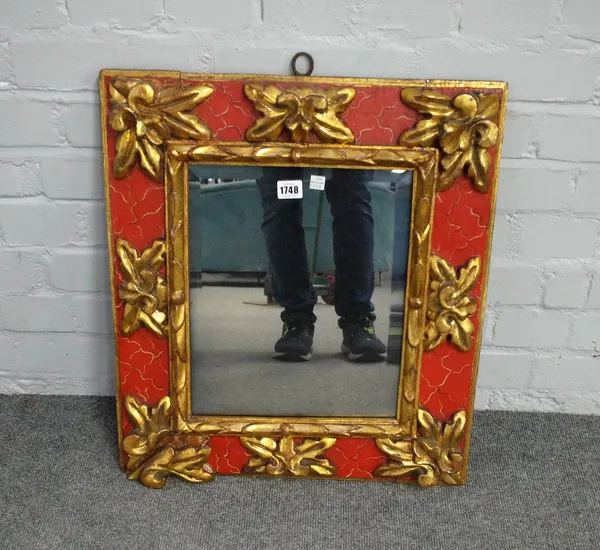 An early 20th century Spanish parcel gilt red painted square wall mirror, with relief carved floral decoration, 51cm wide x 57cm high.