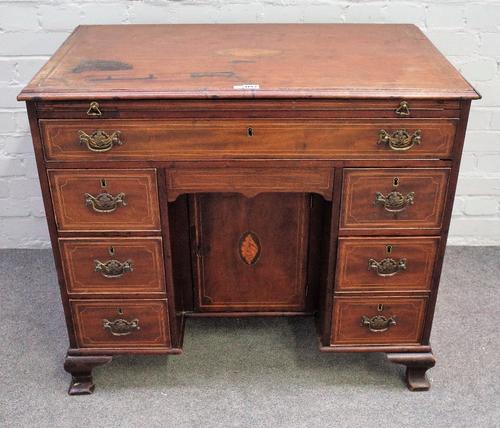 A mid-18th century inlaid mahogany kneehole writing desk with brushing slide over one long and seven short drawers about the knee hole cupboard, on og