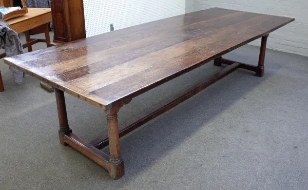 An 18th century and later oak refectory table with cleated plank top on four turned supports united by stretcher, 117cm wide x 309cm long.