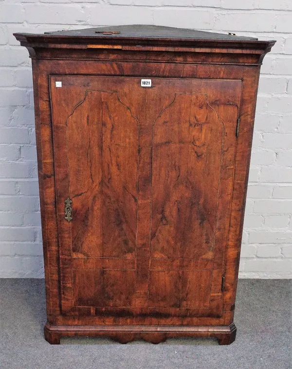 An early 18th century inlaid oak hanging corner cupboard with shaped lower frieze, 81cm wide x 117cm high.