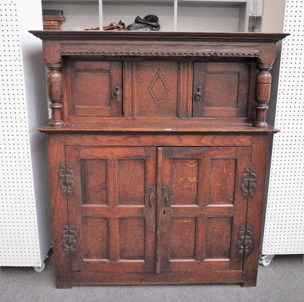 A 17th century oak court cupboard with two pairs of panelled cupboards flanked by turned columns, detailed 'HF 1630', 131cm wide x 150cm high.