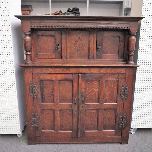 A 17th century oak court cupboard with two pairs of panelled cupboards flanked by turned columns, detailed 'HF 1630', 131cm wide x 150cm high.