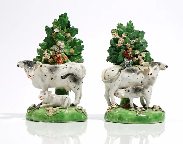 A pair of Derby porcelain cow and calf groups, early 19th, each before a flowering tree on a grassy mound base, unmarked, (a.f), each approx. 16cm. hi