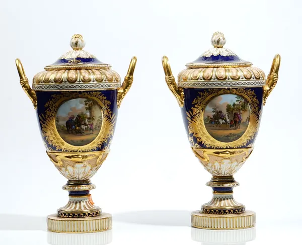 A pair of Berlin porcelain cobalt blue and apricot ground two- handled vases and covers, late 19th century, each painted each side after Philips Wouve