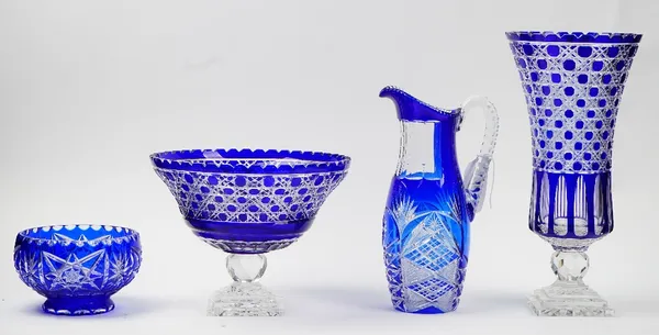 Four pieces of blue flashed glass, 20th century, comprising; a large bowl raised on a facet cut knop and stepped square base, 24cm. high; a matching t