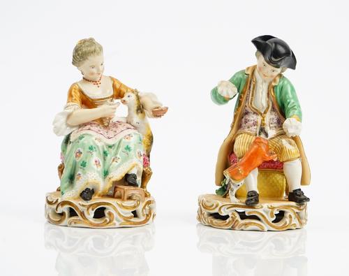 A pair of Derby porcelain figures, early 19th century, modelled as a seated boy playing with a `Macaroni dog' and a girl feeding a cat, incised No. 36