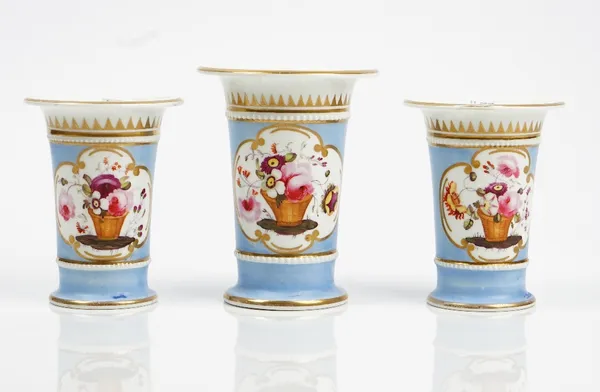 A garniture of three Ridgway porcelain spill vases, circa 1820, each painted with a basket of flowers inside beaded borders against a blue ground, pai