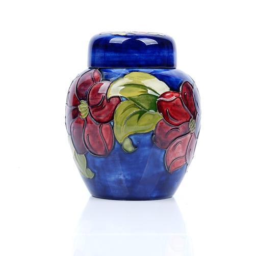 A Walter Moorcroft clematis pattern ginger jar and cover, tube lined against a blue ground, with original paper label, green painted initials, 15cm. h