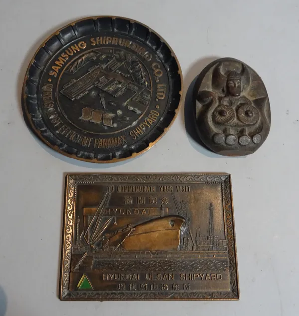 A mid-20th century Scandinavian iron paperweight, 11cm wide, and two composite metal shipping wall plaques, 10cm wide, (3).