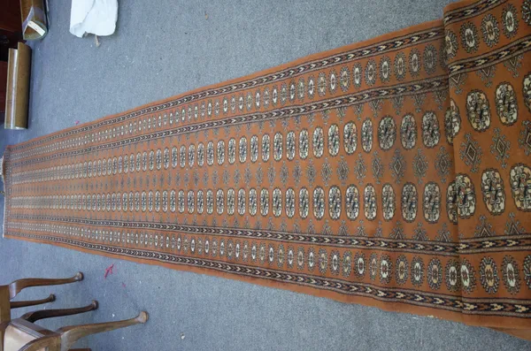 An Indian Bokhara runner with a brown field, 470cm x 80cm.