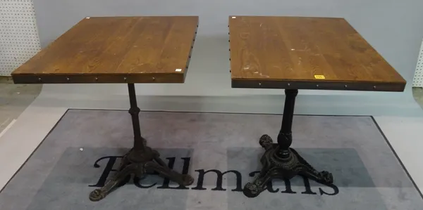 A pair of modern hardwood square occasional tables on cast iron bases, 60cm wide x 74cm high, (2).