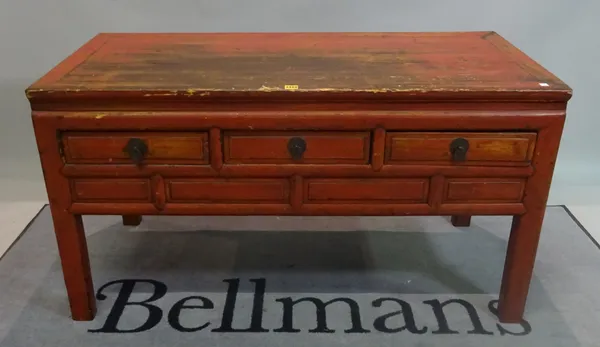 An early 20th century red painted Chinese low side table with three short drawers on block supports, 129cm wide x 72cm high.