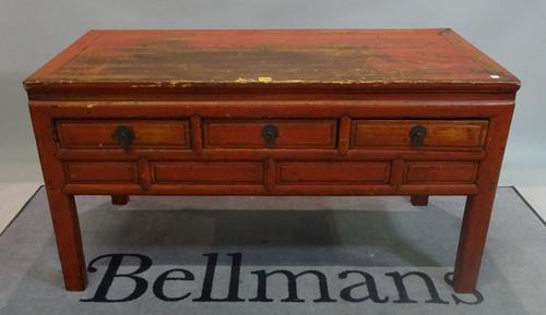 An early 20th century red painted Chinese low side table with three short drawers on block supports, 129cm wide x 72cm high.