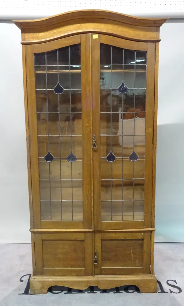 An early 20th century oak floor standing bookcase with lead lined glazed doors, over cupboard base, 100cm wide x 198cm high.