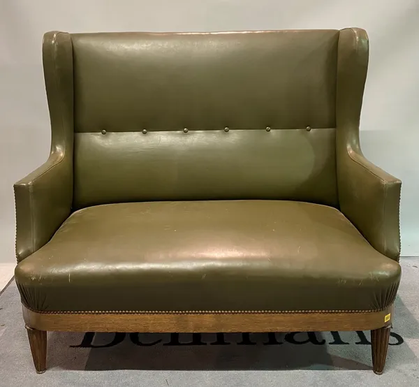 An early 20th century oak framed wingback two seater sofa on reeded tapering supports, 128cm wide x 111cm high.